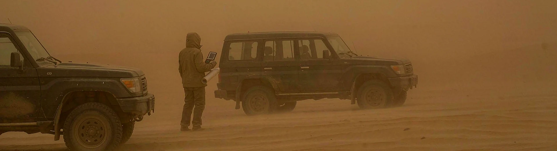 Desert convoy on sand dunes during a sandstorm with a handheld GPS navigator